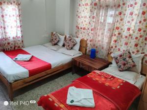 2 camas en una habitación con sábanas y cortinas rojas en Hotel Noryang, en Gangtok 8 fotos más