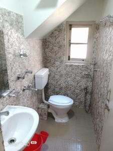 Un baño con inodoro, lavabo y ventana. en Hotel Noryang, en Gangtok