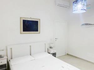 a white bedroom with a bed and a picture on the wall at Villa Lina in Castiglioncello