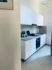a white kitchen with white cabinets and a sink at Villa Lina in Castiglioncello