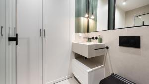 une salle de bains blanche avec un lavabo et un miroir dans l'établissement Flatbook - Studio Yacht Park Gdynia, à Gdynia