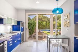 una cocina con armarios azules y una mesa con taburetes en Villa El Cenador - Solo Familias, en Roche