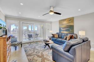 sala de estar con sofá azul y ventilador de techo en Beach Club Villa 12 by Wild Dunes, Oceanfront Condo, en Isle of Palms