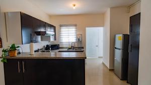 a kitchen with black cabinets and a stainless steel refrigerator at Caribbean Tropical Villa - Free Electricity Included in Punta Cana