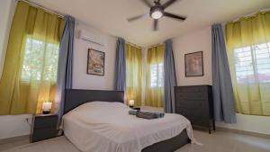 a bedroom with a bed and two windows at Caribbean Tropical Villa - Free Electricity Included in Punta Cana