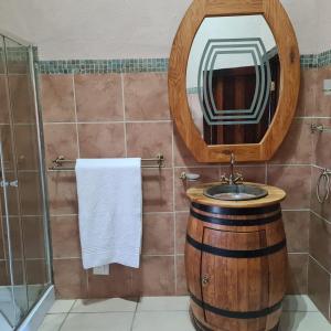a bathroom with a barrel sink and a mirror at Duckpond Lodge in Oudtshoorn