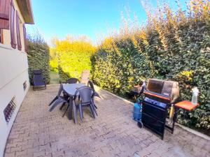 a patio with a table and chairs and a grill at L'Evasion, maison spacieuse, véranda, parking in Saint-André-de-Cubzac +23 photos