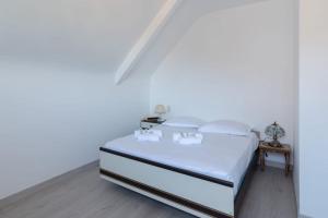 a white bedroom with a bed with white sheets at Doutreleau - Wifi - Parking in Saint Malo