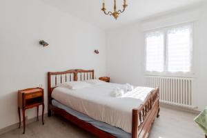 a bedroom with a bed with white sheets and a chandelier at Doutreleau - Wifi - Parking in Saint Malo