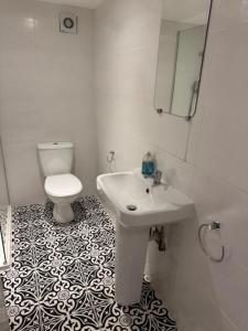 a white bathroom with a sink and a toilet at Valletta House Holiday Apartments in Skegness