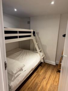 a bedroom with a bunk bed with white sheets at Valletta House Holiday Apartments in Skegness