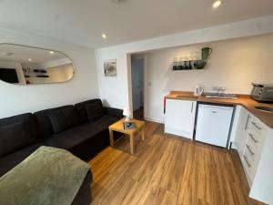 a living room with a black couch and a kitchen at Valletta House Holiday Apartments in Skegness