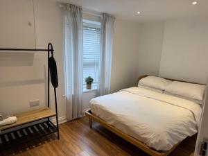 a white bedroom with a bed and a window at Valletta House Holiday Apartments in Skegness