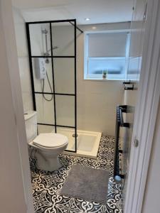 a bathroom with a toilet and a glass shower at Valletta House Holiday Apartments in Skegness