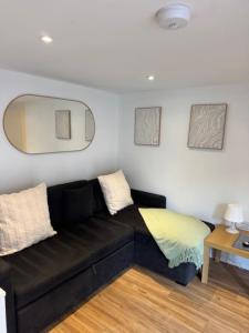 a black couch in a living room with a mirror at Valletta House Holiday Apartments in Skegness