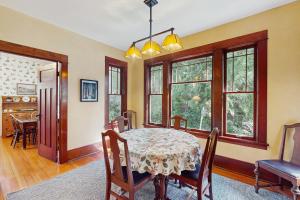 a dining room with a table and chairs and windows at Sunny Hill Farmhouse in Fort Ward
