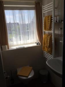 a bathroom with a sink and a toilet and a window at Haus Seelord in Wenningstedt