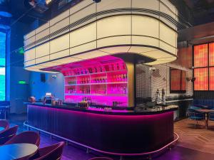 un bar in un ristorante con illuminazione rosa di Adagio Doha a Doha
