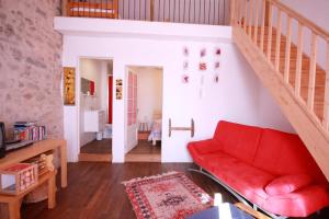 a living room with a red couch and stairs at Beautiful country cottage in Limousin Natural Park in Bussière-Galant