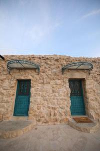 a stone building with two green doors on it at The Inn in Jbeil +5 photos