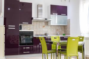 a kitchen with purple cabinets and yellow chairs at Andrea's Dépendance in Letojanni +10 photos