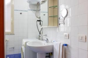 a white bathroom with a sink and a mirror at Andrea's Dépendance in Letojanni