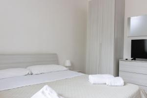 a white bedroom with two beds and a flat screen tv at Andrea's Dépendance in Letojanni