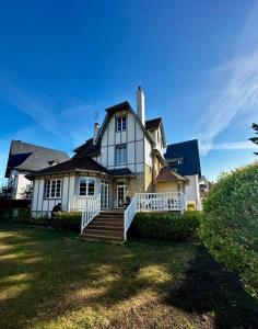 a large white house with a porch and stairs at Villa Georgia in Bénerville-sur-Mer