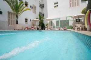a swimming pool in a hotel with tables and chairs at Hotel Monte Alegre in Rio de Janeiro