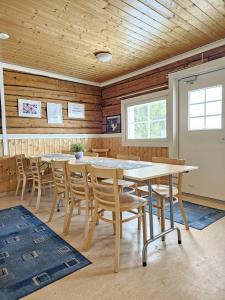 a dining room with wooden walls and tables and chairs at Pohjanranta Cottages in Keminmaa