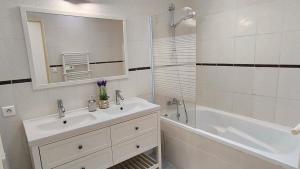 a bathroom with a sink and a tub and a mirror at Maison tout confort belle terrasse sud in Sigean