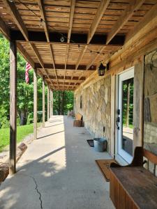 a covered walkway with benches and a stone wall at Busse's Roost Cozy Mountain House in Cosby