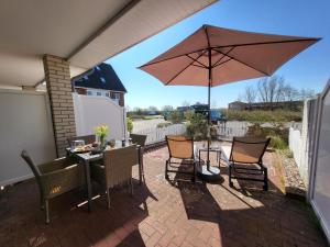 圣彼得奥尔丁Ferienwohnung Deichglück - Direkt am Böhler Sandstrand的带桌子和遮阳伞的露台