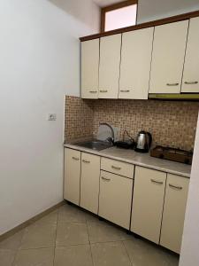 a kitchen with white cabinets and a sink at Dario's Apartaments in Orikum