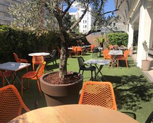 an outdoor patio with tables and chairs and a tree at Ibis Styles Lyon Gorge de Loup Saphir in Lyon