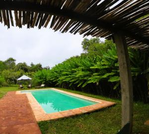 a swimming pool in a yard with a pergola at Granja La Lechuza Ecolodge in Oberá