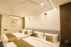 two beds in a hotel room with white walls at The Meera Hotel in Ujjain