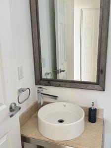Un baño con un lavabo blanco y un espejo. en Casa Chanel México, en Playa del Carmen