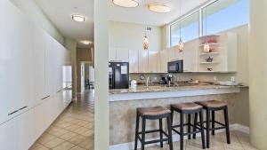 a kitchen with white cabinets and bar stools at Crescent Siesta Key Charmer in Siesta Key