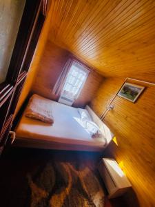 a small bed in a wooden room with a window at Cabana Baile Chirui Ciubar in Băile Chirui