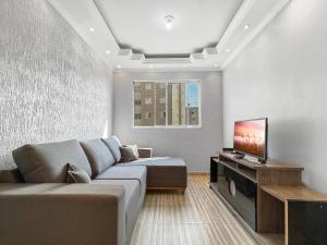a living room with a couch and a flat screen tv at Plaza Shopping Barbecue Court 3 bedrooms in Carapicuíba