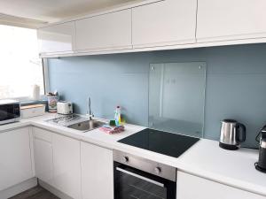 a kitchen with white cabinets and a sink at 26 Piazza - stunning seaviews of Porthmeor beach in St Ives