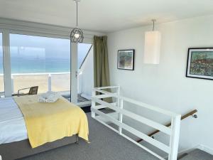a bedroom with a bed and a view of the beach at 26 Piazza - stunning seaviews of Porthmeor beach in St Ives