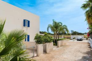 a white house with blue windows and a driveway at Spuma di Mare - Riccio in San Vito lo Capo