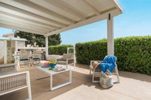 a patio with white chairs and a table and awning at Spuma di Mare - Riccio in San Vito lo Capo +15 photos