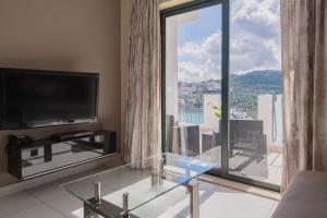 圣保罗湾城Xemxija Bay Hotel的一间带电视和玻璃桌的客厅