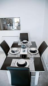 a black dining table with black chairs and plates and wine glasses at TMS Chic 3BDR house! Colchester! in Abberton +23 photos