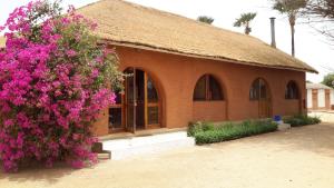 un petit bâtiment avec des fleurs roses devant lui dans l'établissement Baobab Lodge, à Fadial