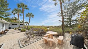 a patio with a table and benches and palm trees at Las Hermanas 4 in Longboat Key