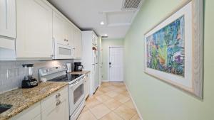 a kitchen with white cabinets and a painting on the wall at Las Hermanas 4 in Longboat Key